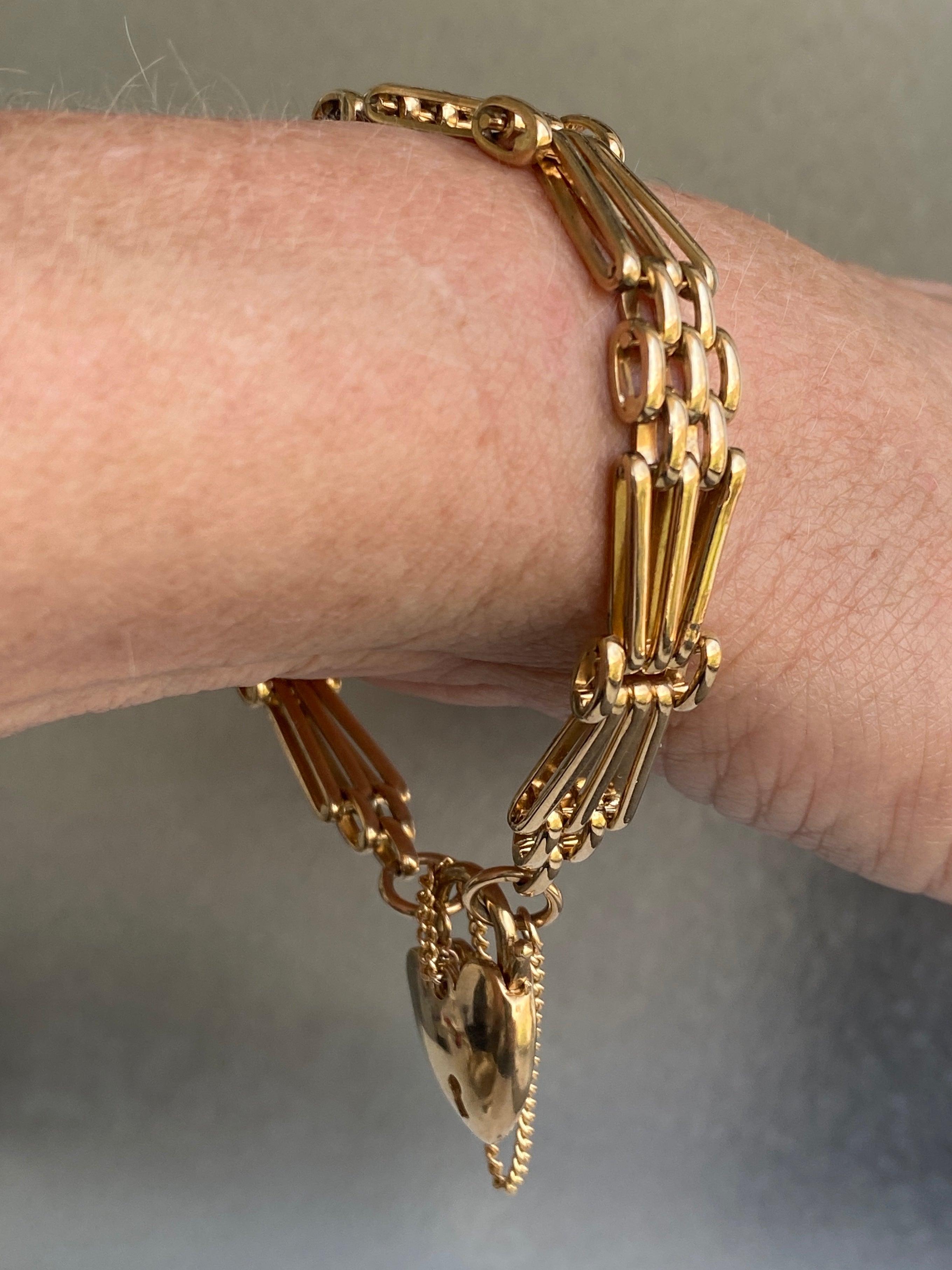 A vintage 9ct yellow gold gate-link bracelet with a heart-shaped padlock.