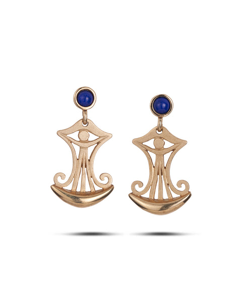 A pair of gold-toned dangle earrings with a stylized eye-of-providence motif, featuring a small round blue stone at the top and a crescent-shaped lower section, shown on a white background.