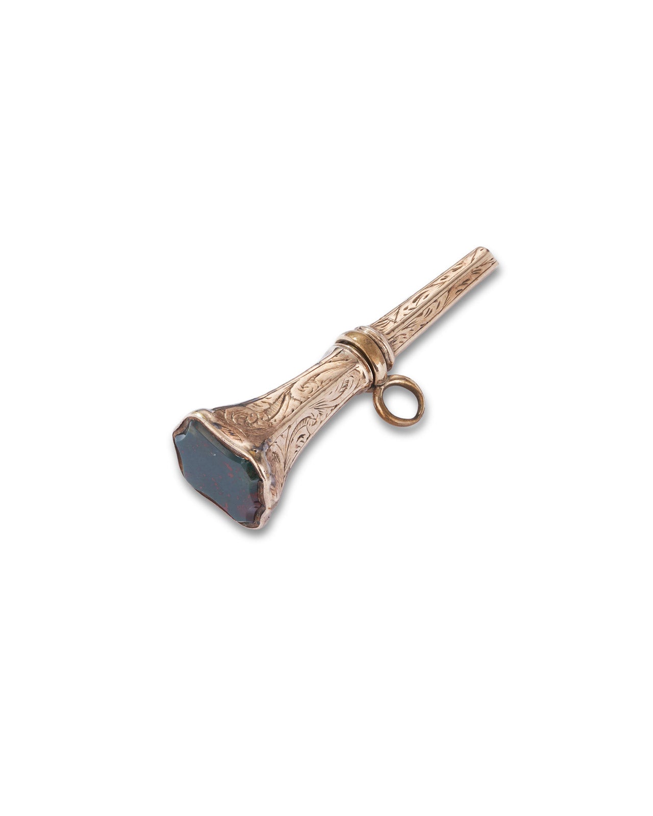A vintage gold watch key with engraved detailing and a dark faceted stone on the front, shown on a plain white background.