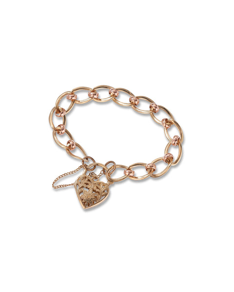 A yellow and rose gold chain bracelet with a heart-shaped filigree padlock, displayed on a clean white background.